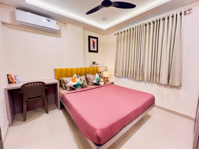 Modern bedroom with double bed, air conditioner, study desk, and cozy interior in a fully furnished service apartment
