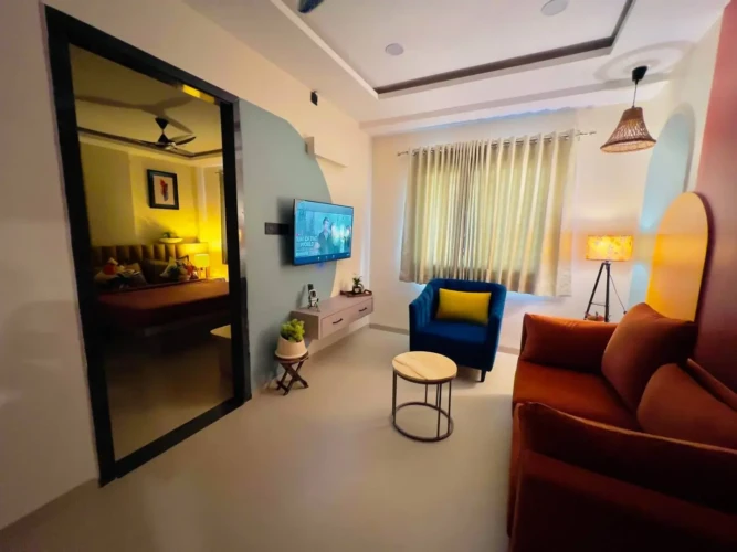 1BHK service apartment with modern living room, bedroom view, wall-mounted TV, and stylish furniture setup