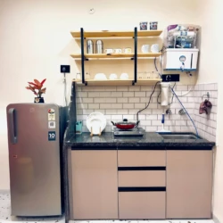 modern kitchen with shelves, RO purifier, stove and refrigerator in service apartment