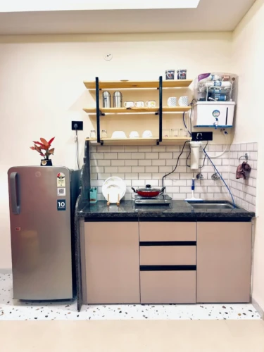 modern kitchen with shelves, RO purifier, stove and refrigerator in service apartment