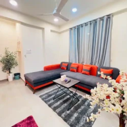 Modern living room of a private & cozy studio with L-shaped sofa, wall-mounted TV, and stylish decor setup