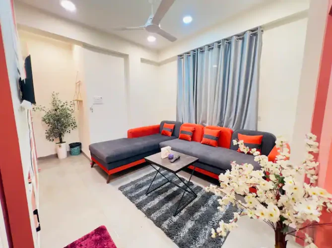 Modern living room of a private & cozy studio with L-shaped sofa, wall-mounted TV, and stylish decor setup