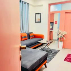 Modern living room of a private & cozy studio with L-shaped sofa, wall-mounted TV, and stylish decor setup