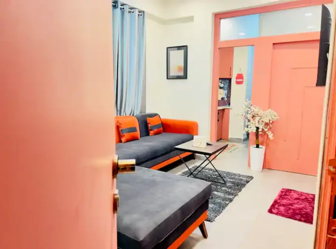 Modern living room of a private & cozy studio with L-shaped sofa, wall-mounted TV, and stylish decor setup